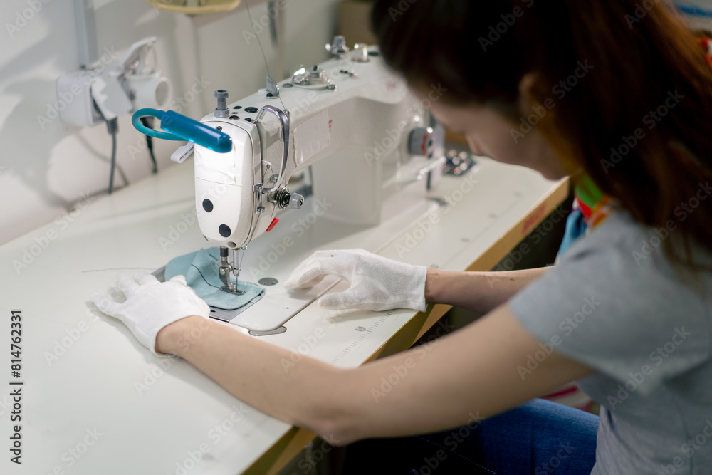 professional dry cleaner young girl hems a patch on a sweater with a sewing machine
