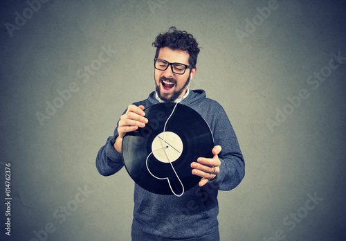 Happy singing young man listening music on  a vinyl record  photo