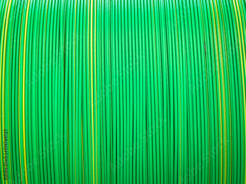 Vivid green and yellow plastic coated cables tightly coiled, showcasing a symmetrical and colorful pattern.