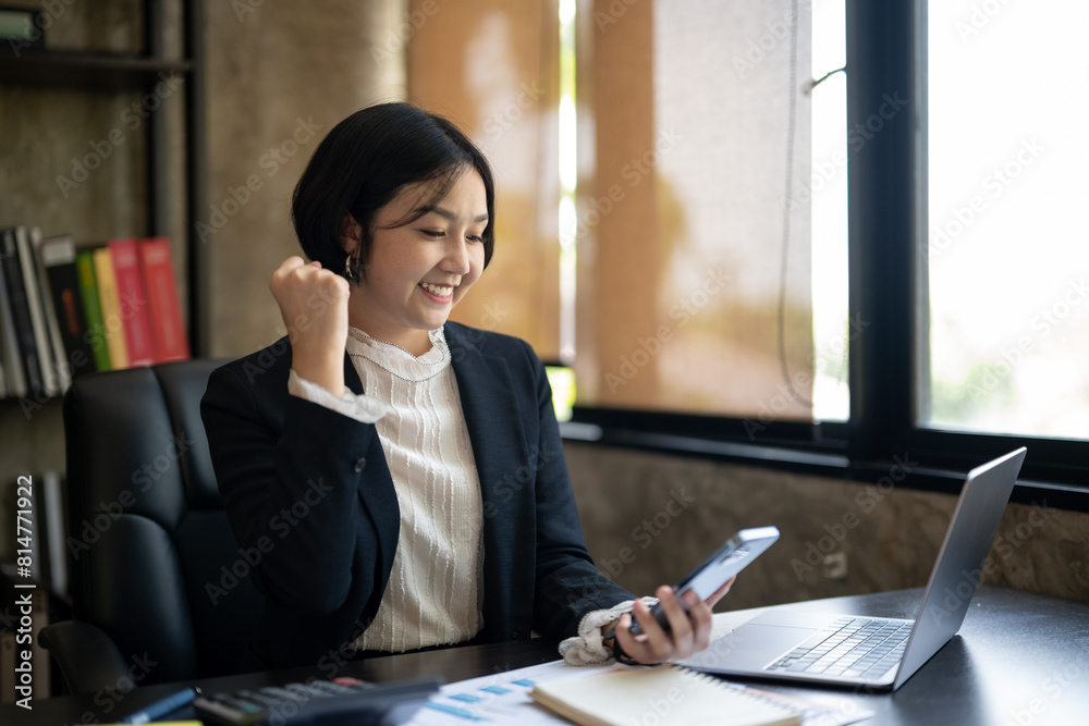A woman in a business suit is smiling and holding a cell phone