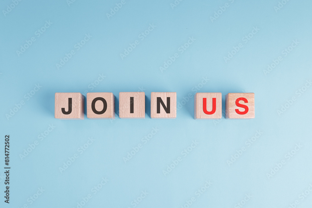 A wooden cube block in pastel blue background with the letters JOIN US written on it in concept of membership subscription register. A wooden cube block in pastel blue background with the letters JOIN US written on it in concept of membership subscription register.