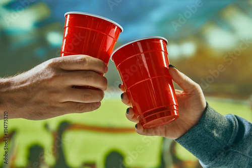People clinking red mugs with beer at football stadium during match. Celebrating successful game. Concept of game, leisure, championship, tournament, emotions © master1305