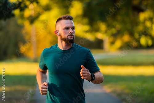 A young sporty man running or jogging at the park listening to music on wireless headphones active healthy lifestyle.