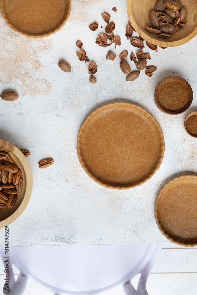 Baked pie crusts on a table with pecans Baked pie crusts on a table with pecans