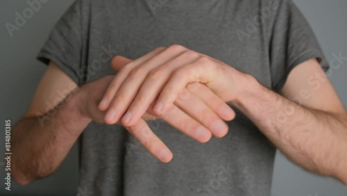 A man in a gray T-shirt rubs his hands close-up at the camera. photo