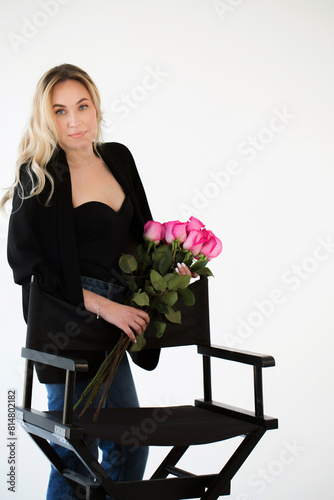 A beautiful woman in a black suit with a bouquet of roses