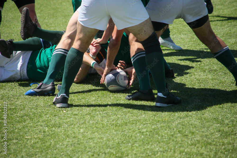 Group of men playing rugby on grass field, tackling and passing ball in action-packed match. Group of men playing rugby on grass field, tackling and passing ball in action-packed match.