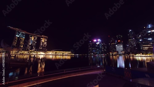 Singapore city, Singapore - 16th march, 2023: Tourist on bench use phones on viewpoint on marina bay waterfront in singapore. Scenic night scape viewpoint Singapore panorama