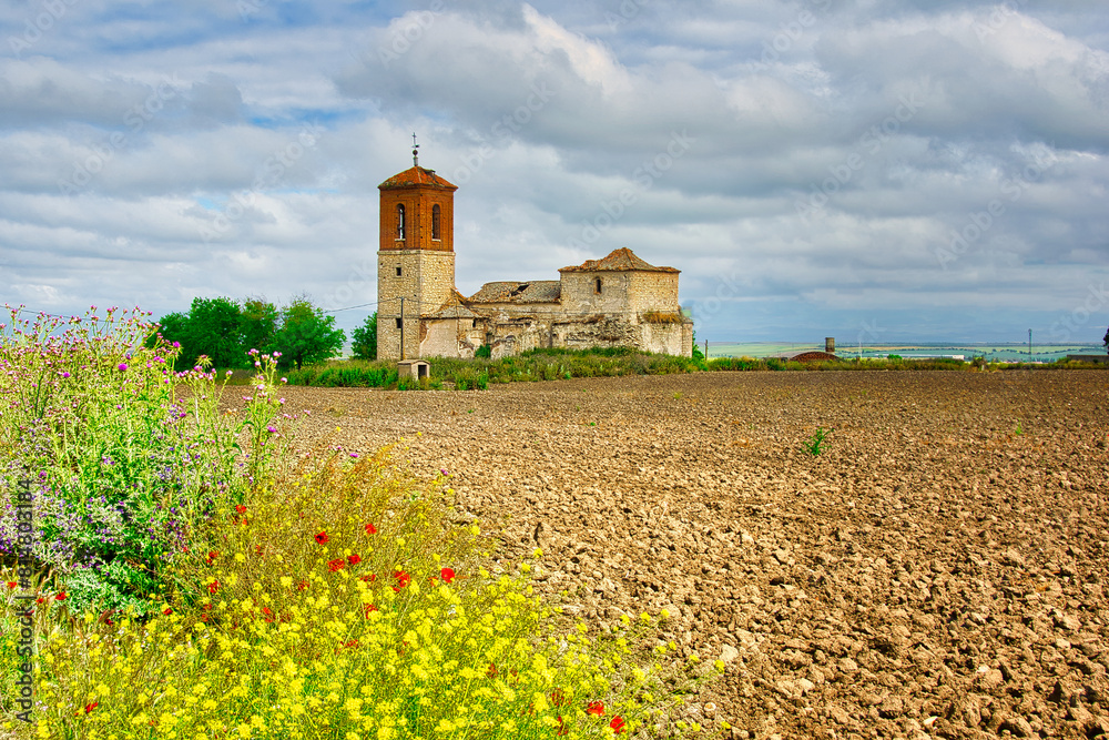 Plowed field with the ruined Church of the abandoned town of Caudilla, Toledo (Spain), in the background