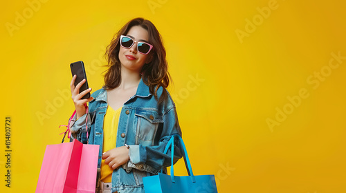 Photo portrait view of woman holding phone and shopping bags isolated on yellow background