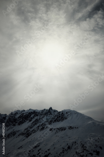 Sunset light through clouds over snowy mountains