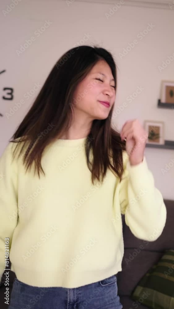 Vertical. young Asian girl has fun dancing alone in living room. Excited Chinese female influencer doing viral dance moves for social media. Single generation z people enjoying free time at home. Vertical. young Asian girl has fun dancing alone in living room. Excited Chinese female influencer doing viral dance moves for social media. Single generation z people enjoying free time at home.