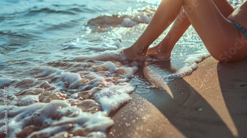 Female legs while sunbathing at the beach and chilling in a sea water photo