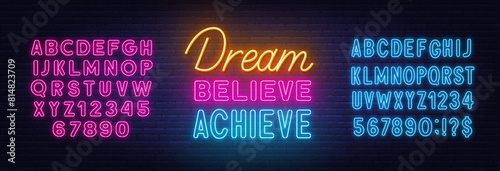 Dream Believe Achieve neon lettering on brick wall background