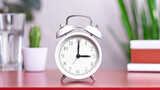 Classic white clock on a table. The clock hand points at 03:00, 15:00 close up photo