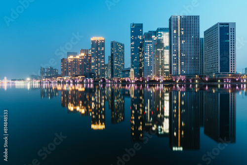 Skyscrapers reflection upon a river in evening, just after sunset, in Tongzhou District, Beijing, China photo