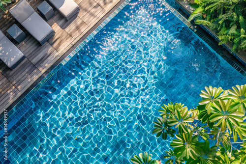 Up view copter photo of the swimming pool with transparent turquoise surface water, tropical trees and sun loungers