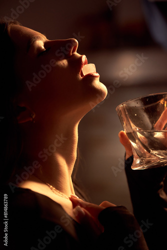 A beautiful girl erotically holds an ice cube with her lips.