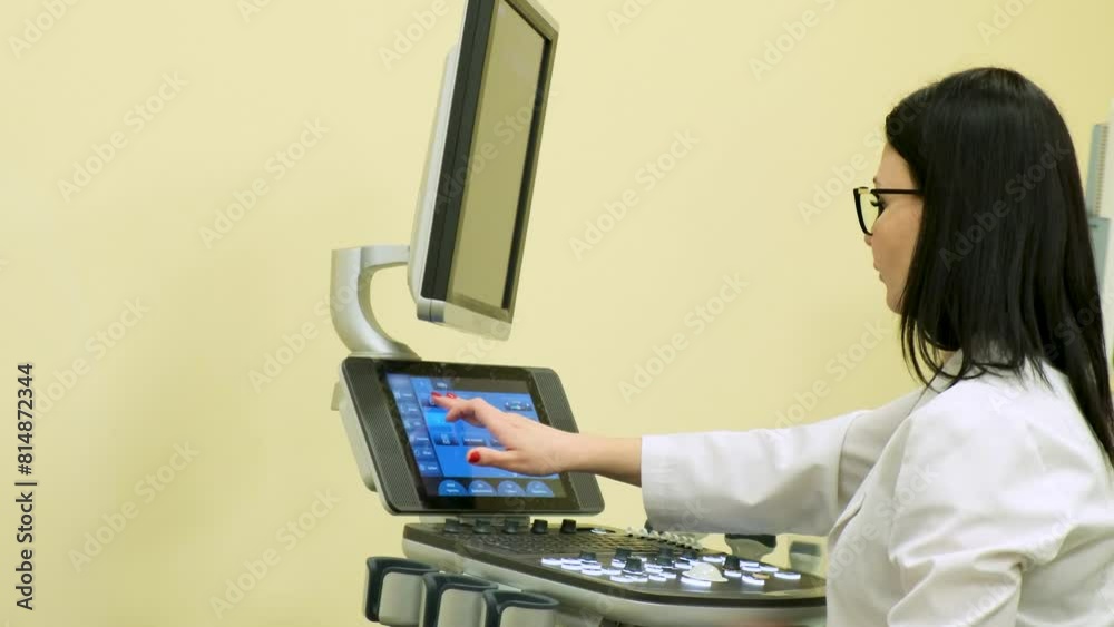 A woman doctor works at an ultrasound machine in a clinic. A woman doctor works at an ultrasound machine in a clinic.