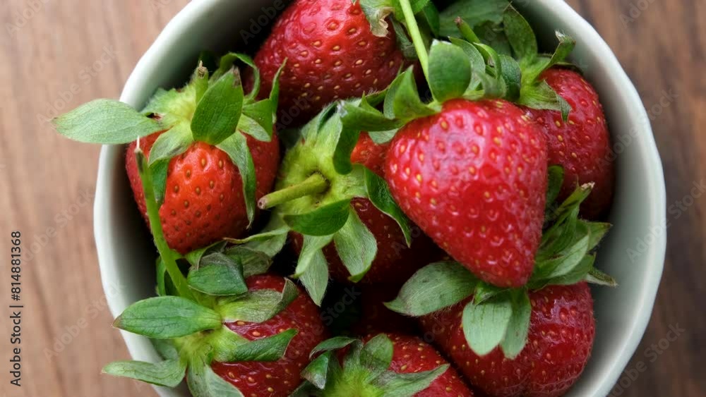 Top view of a rotating bowl of strawberries on a wooden surface Top view of a rotating bowl of strawberries on a wooden surface