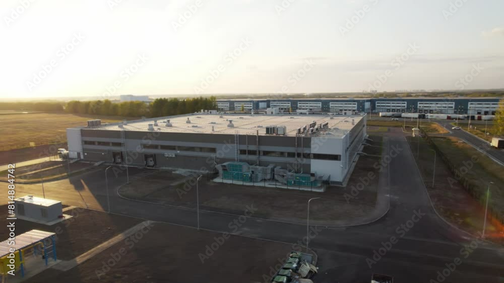 Exterior of warehouse features large doors and windows. Warehouse surrounded by car park with designated parking areas for trucks Exterior of warehouse features large doors and windows. Warehouse surrounded by car park with designated parking areas for trucks