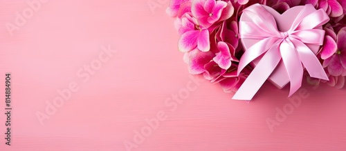 A gift heart is presented in a pink heart box adorned with a pink bow and pink hydrangea flowers The copy space image features a bright fuchsia background symbolizing the love concept This Valentine