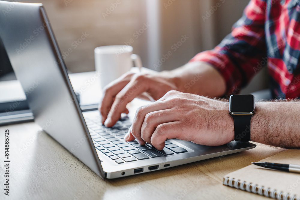 Cropped shot of man's hands using laptop at home office. Hands of adult contemporary office manager over laptop keypad during work over new business project by table Cropped shot of man's hands using laptop at home office. Hands of adult contemporary office manager over laptop keypad during work over new business project by table
