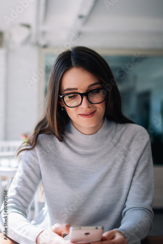 Attractive hipster girl intdoors check mail by new cellular, positive woman sending text messages via modern mobile phone, female journalist searching information for article using smartphone