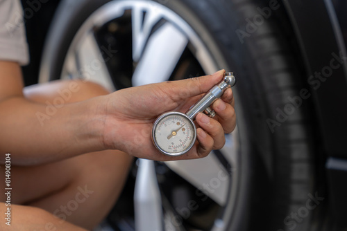 The woman is checking the tire pressure of her car before heading out for a trip.