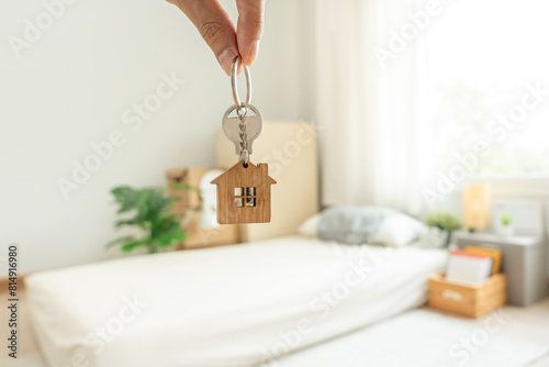Moving house, relocation. man hold key house keychain in new apartment, inside the room was a cardboard box containing personal belongings and furniture. move in the apartment or condominium