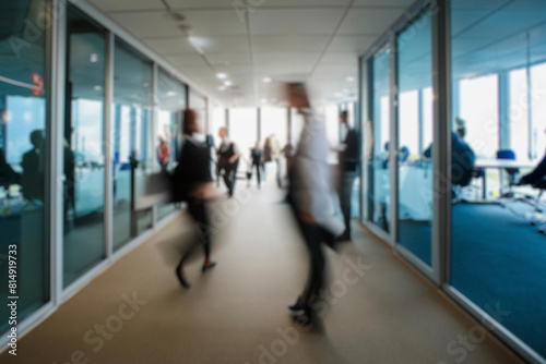 business people walking in the corridor of an business center, pronounced motion blur, crowded bright modern light office movement defocused. office background busy. talking and rushing in the lobby.