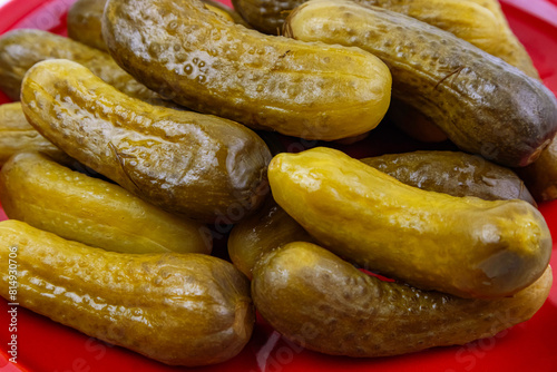 Pickled cucumbers on a large red plate close-up