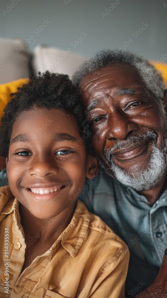 A heartwarming image of an elderly man with a white beard and a young boy with curly hair both smiling and sharing a joyful moment together possibly on a couch. A heartwarming image of an elderly man with a white beard and a young boy with curly hair both smiling and sharing a joyful moment together possibly on a couch.