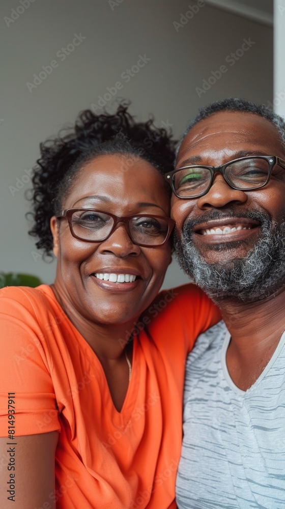 Two smiling adults one with glasses and a beard the other with curly hair embracing each other in a warm indoor setting. Two smiling adults one with glasses and a beard the other with curly hair embracing each other in a warm indoor setting.