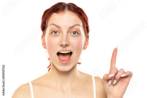 portrait of a young woman with red hair pointing finger up great idea eureka isolated on white background