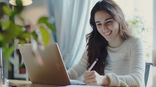 Distance Education Portrait of smiling woman sitting at desk using laptop and writing in notebook taking notes watching tutorial lecture or webinar studying online at home looking at s : Generative AI