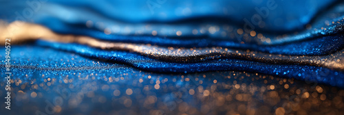 Blue wavy abstract background with gold glitter sparkles. The glitter flakes vary in size and shape, creating a shimmering and textured effect photo