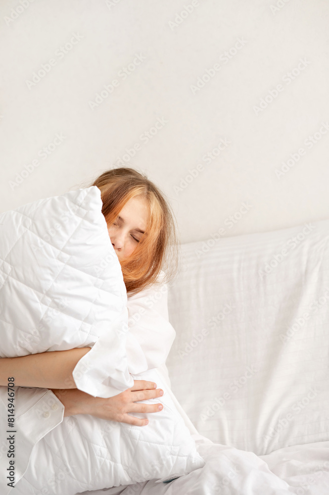 Sleepy teenage girl with eyes closed embracing white pillow in neutral white bedroom, teenagers sleep deficiency, good sleep concept Sleepy teenage girl with eyes closed embracing white pillow in neutral white bedroom, teenagers sleep deficiency, good sleep concept