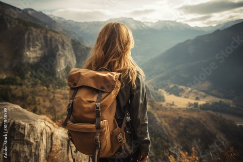 Back view of a woman with backpack gazing at a breathtaking mountainous landscape © juliars