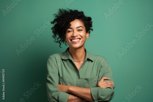 Portrait of a grinning woman in her 30s with arms crossed on pastel green background