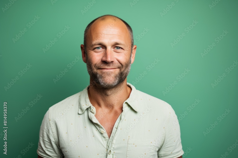 Portrait of a smiling man in his 40s smiling at the camera in pastel green background Portrait of a smiling man in his 40s smiling at the camera in pastel green background