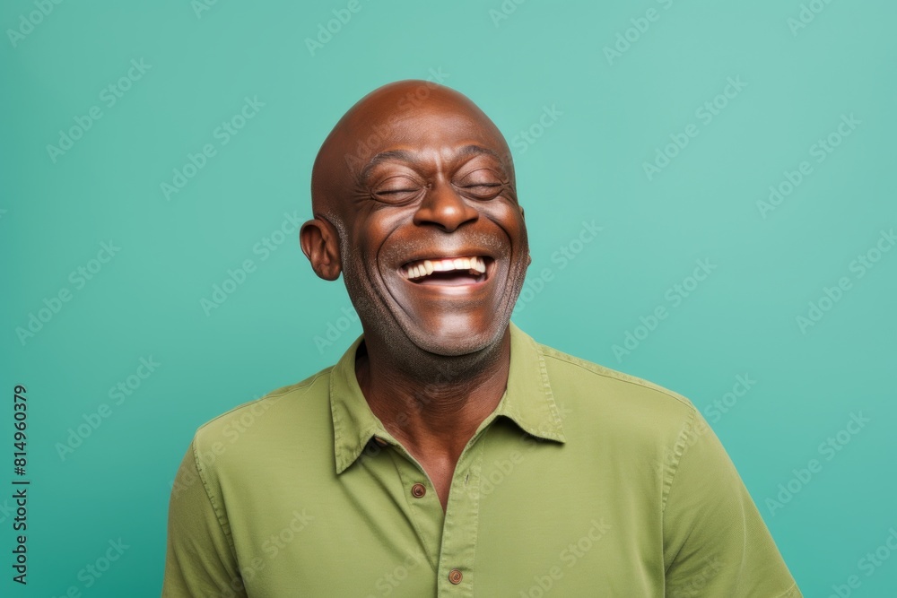 Portrait of a glad afro-american man in his 50s laughing in front of pastel green background Portrait of a glad afro-american man in his 50s laughing in front of pastel green background