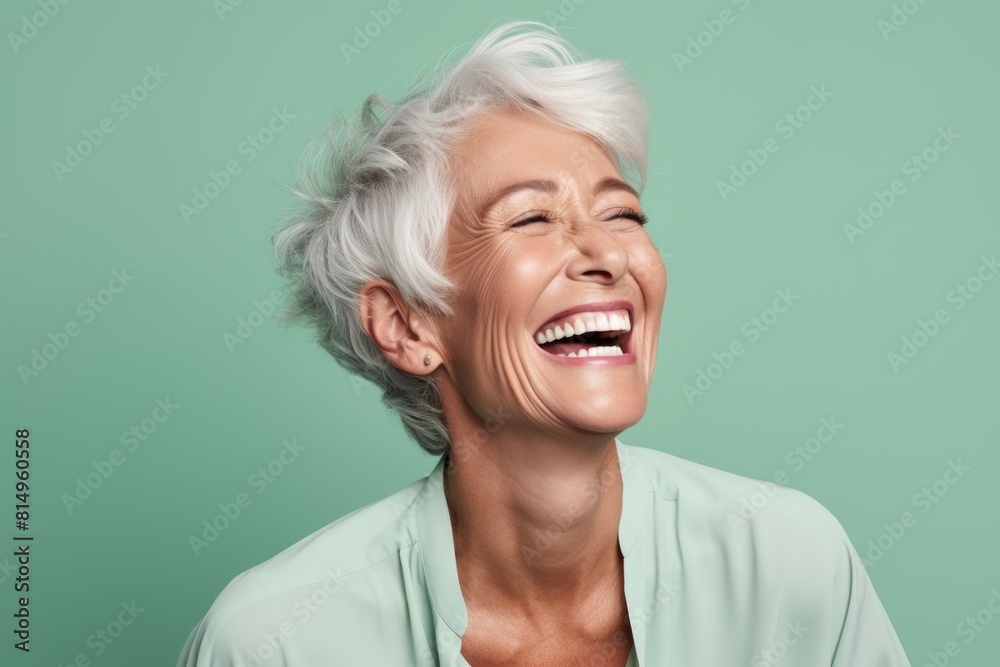 Portrait of a glad woman in her 60s laughing over pastel green background Portrait of a glad woman in her 60s laughing over pastel green background
