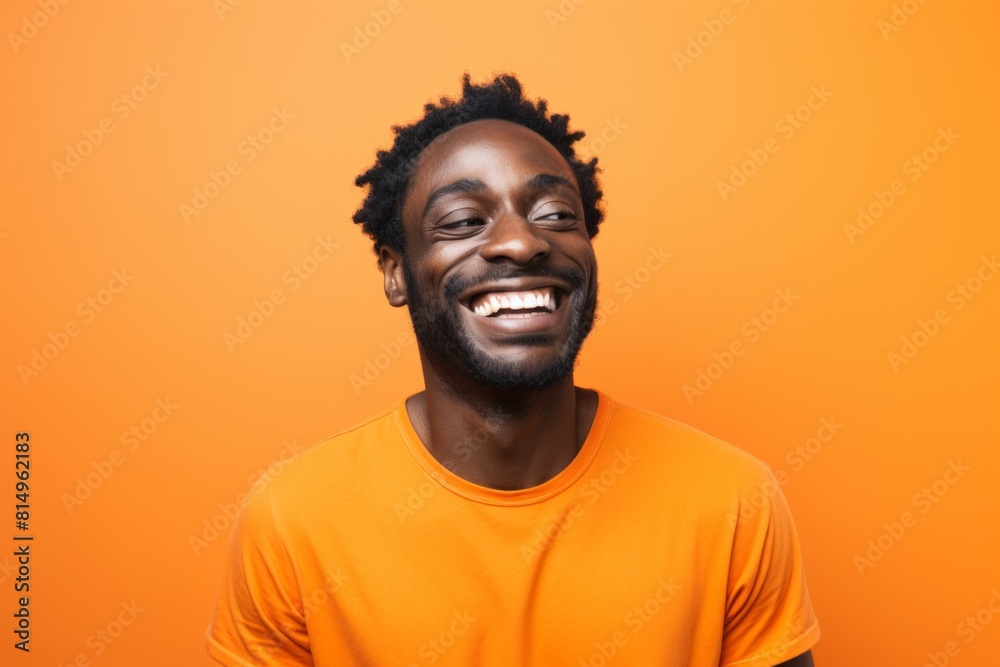 Portrait of a cheerful man in his 30s smiling at the camera over pastel orange background Portrait of a cheerful man in his 30s smiling at the camera over pastel orange background