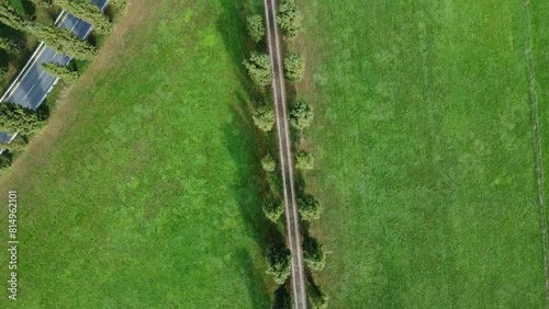 Veduta aerea con drone , lungo una strada rurale nella campagna italiana con un'auto che corre lungo la strada asfaltata vicino ad essa, puoi vedere prati verdi su entrambi i lati  photo