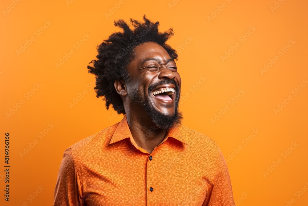 Portrait of a jovial afro-american man in his 40s laughing over pastel orange background Portrait of a jovial afro-american man in his 40s laughing over pastel orange background