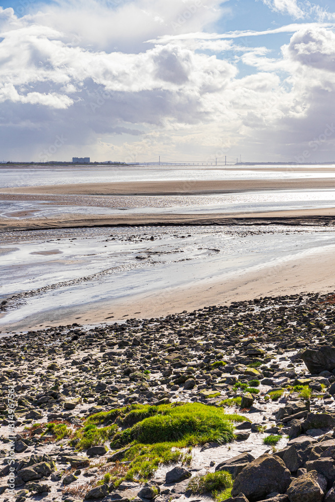 A view across the Severn Estuary at low tide towards Oldbury Power Station and the Severn bridges seen from Lydney Harbour, Gloucestershire, England UK