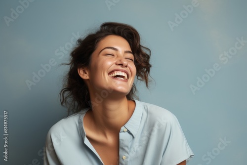Portrait of a satisfied woman in her 30s laughing over pastel gray background