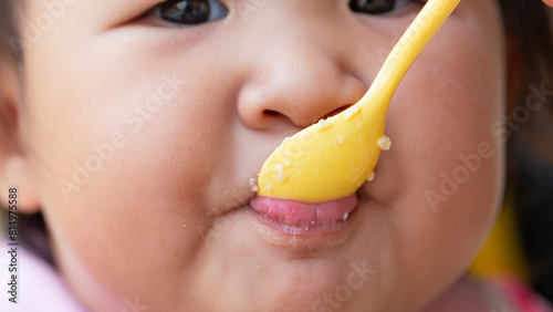 Wallpaper Mural Child eating rice with a spoon close-up,Close up infant baby feeding food on the kid chair Torontodigital.ca