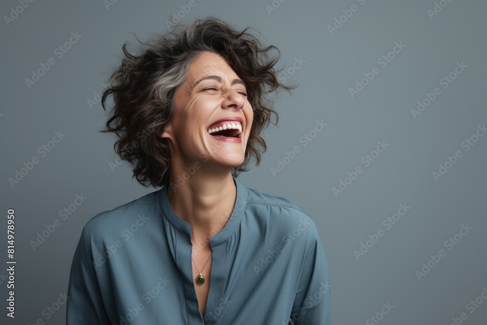 Portrait of a glad woman in her 40s laughing over pastel gray background Portrait of a glad woman in her 40s laughing over pastel gray background